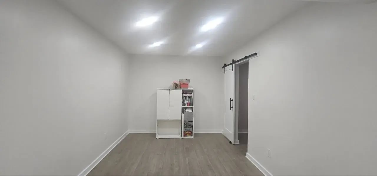 Finished basement room with storage cabinet and sliding door