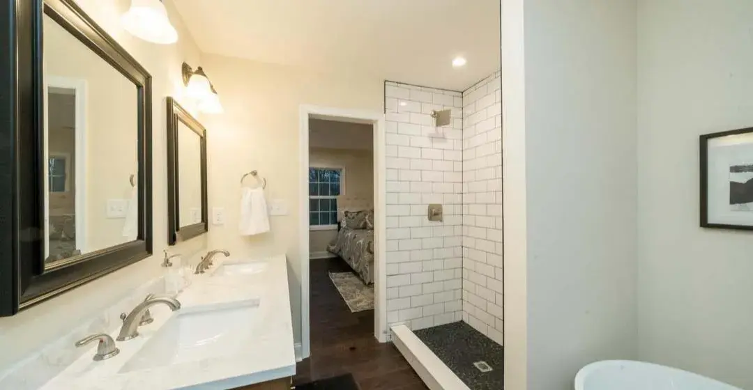 Bathroom double vanity with black-framed mirrors and walk-in tiled shower