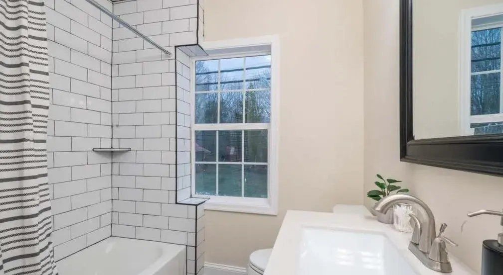 Tub with white subway tile surround next to a modern vanity sink