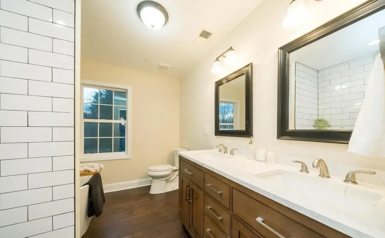 Renovated bathroom with double vanity, white quartz top and subway tile shower