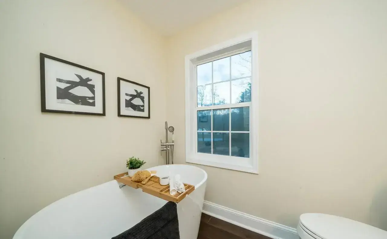 Freestanding soaking tub by the window in the remodeled bathroom