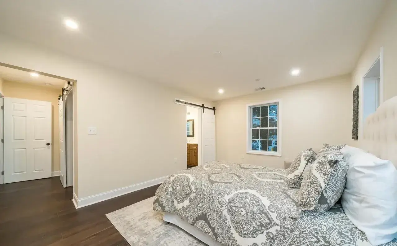 Bright bedroom after renovation with wood floors and barn-style door