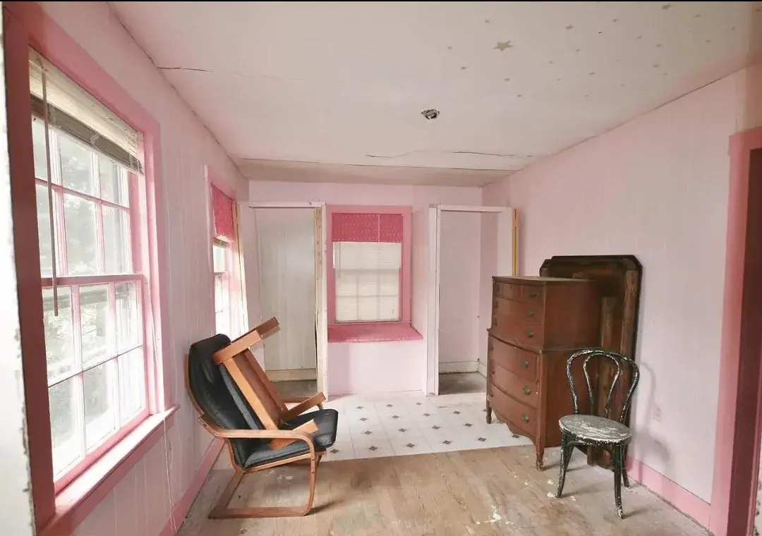 Bedroom with pink walls and worn floors before renovation