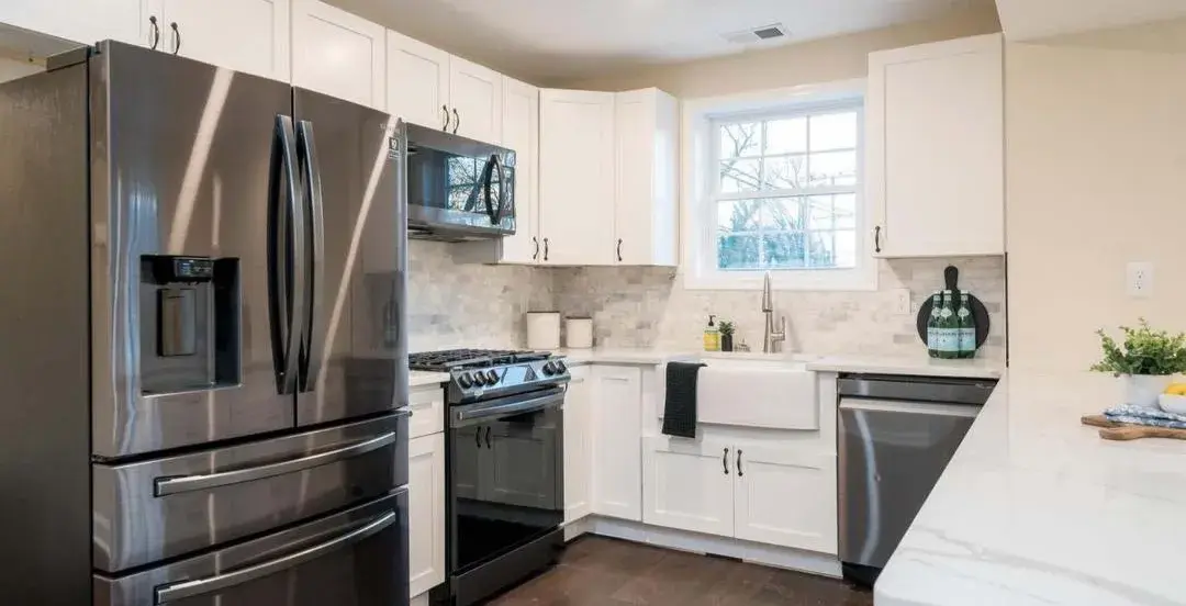 White shaker cabinets, marble-look backsplash and black stainless range