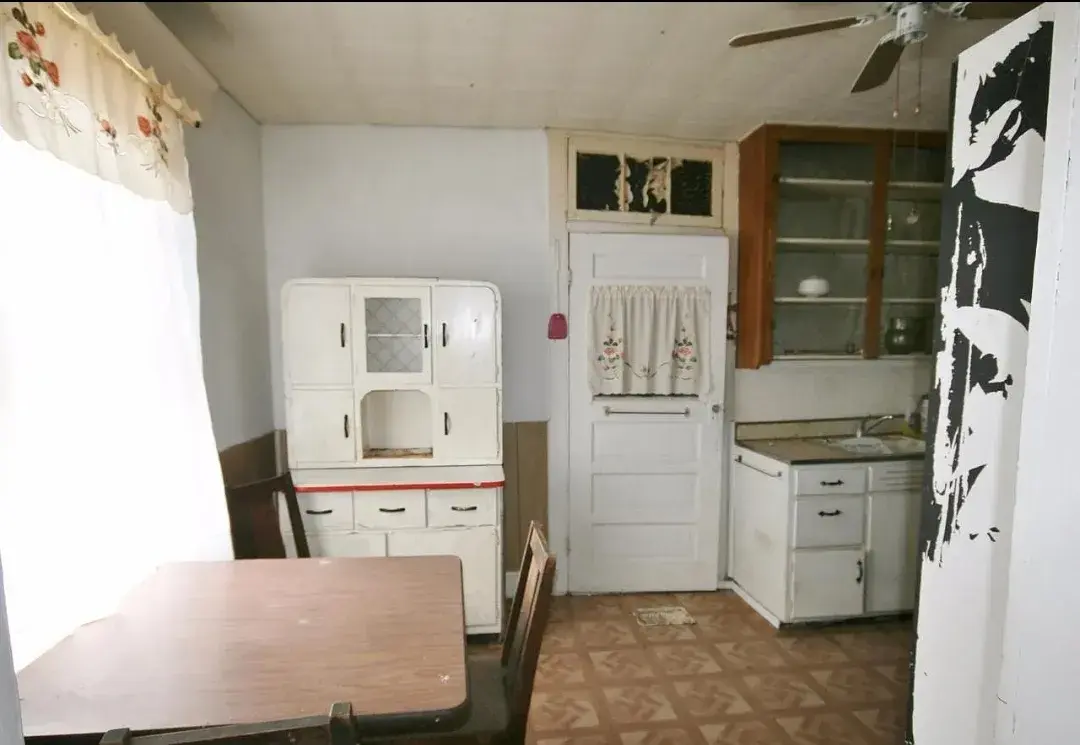 Old kitchen with vintage hutch and worn linoleum floor before remodel