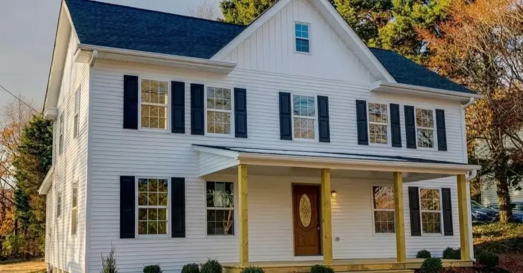 Renovated farmhouse in Solomons, MD with white siding, black shutters and new front porch