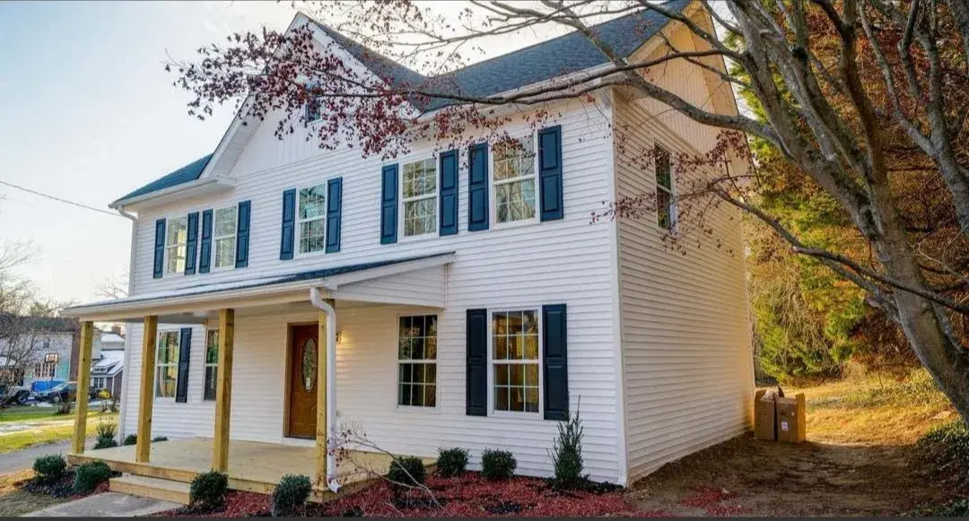 Front corner of the updated house with covered porch and dark shutters