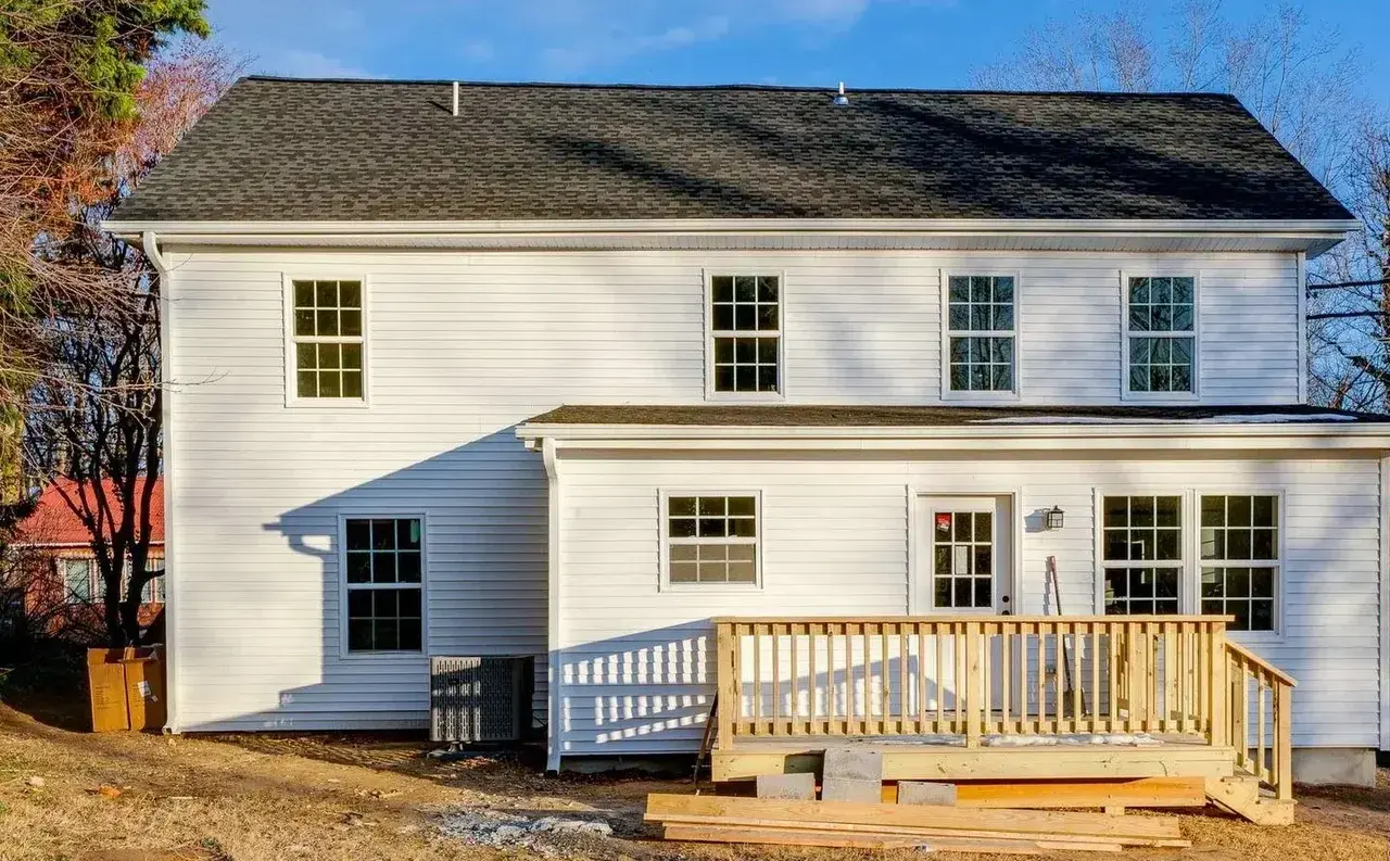 Rear exterior after renovation with fresh white siding and new back deck
