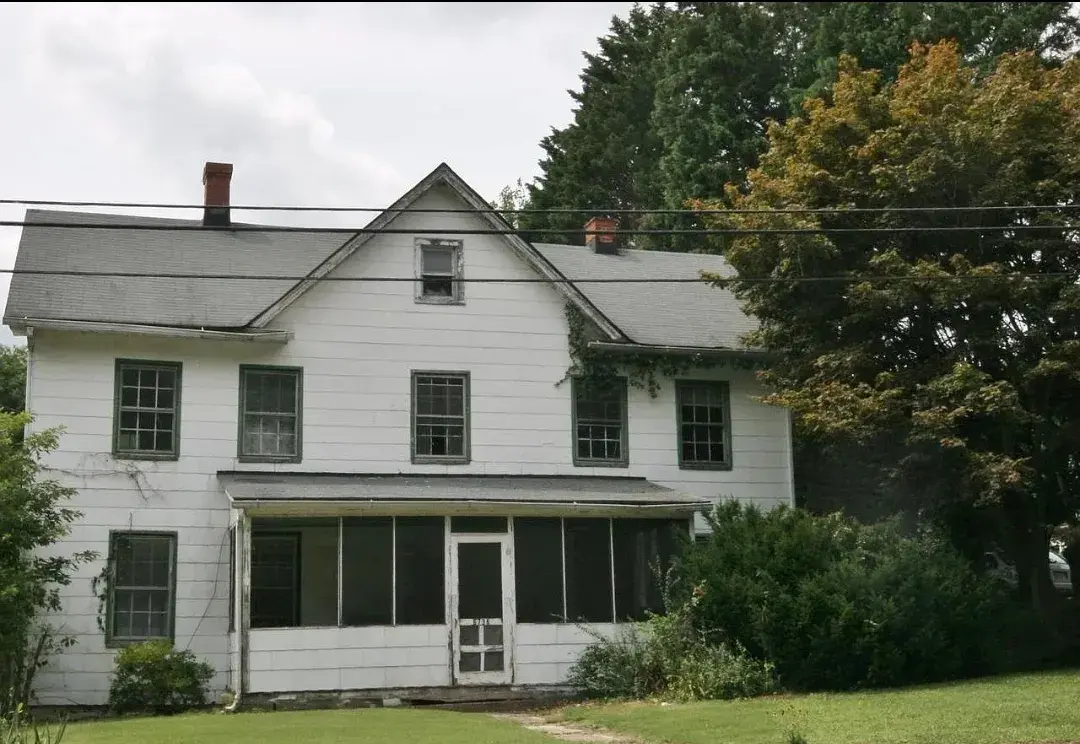 Weathered white house front with enclosed screen porch before exterior repairs