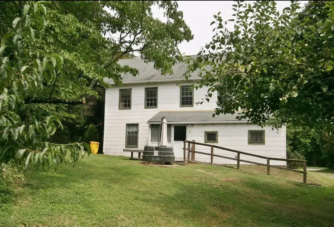 Side of the old house with overgrown yard and worn siding before renovation