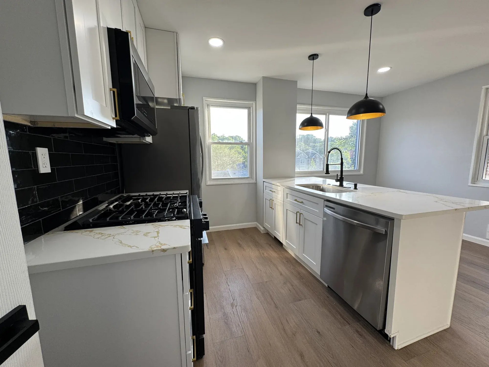Kitchen with gas range, black tile backsplash and stainless steel appliances