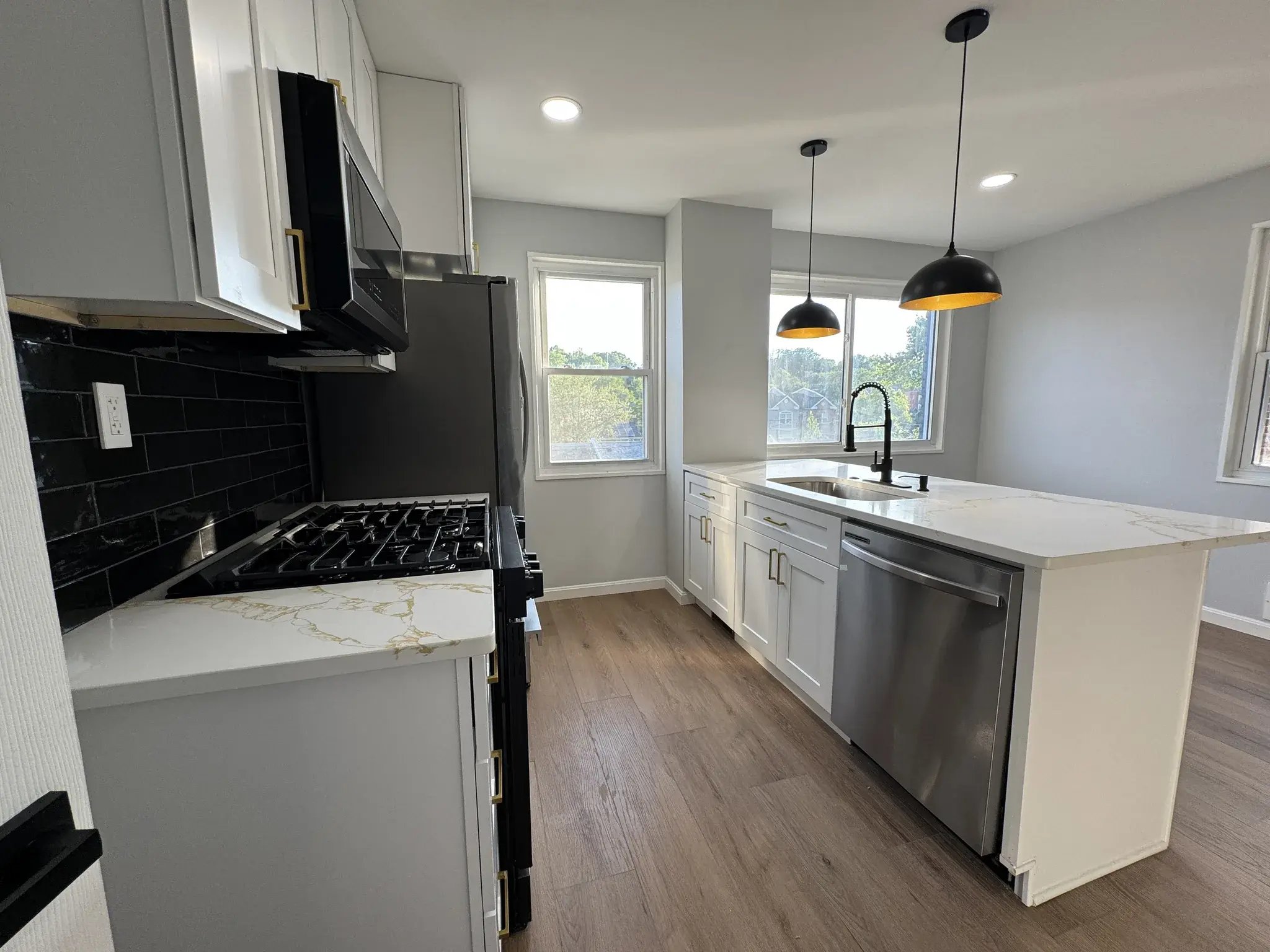 Kitchen with gas range, black tile backsplash and stainless steel appliances