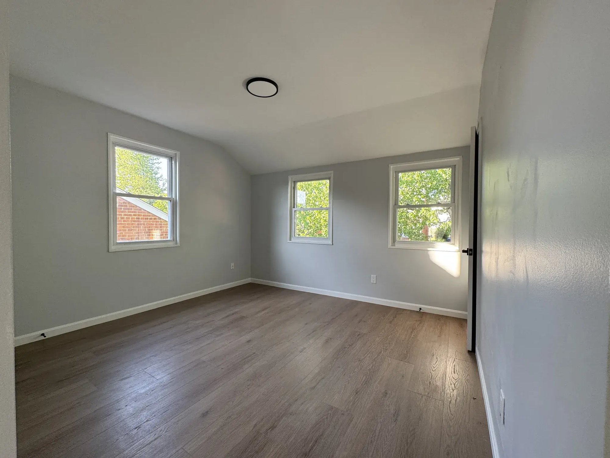 Bright bedroom with three windows and new flooring