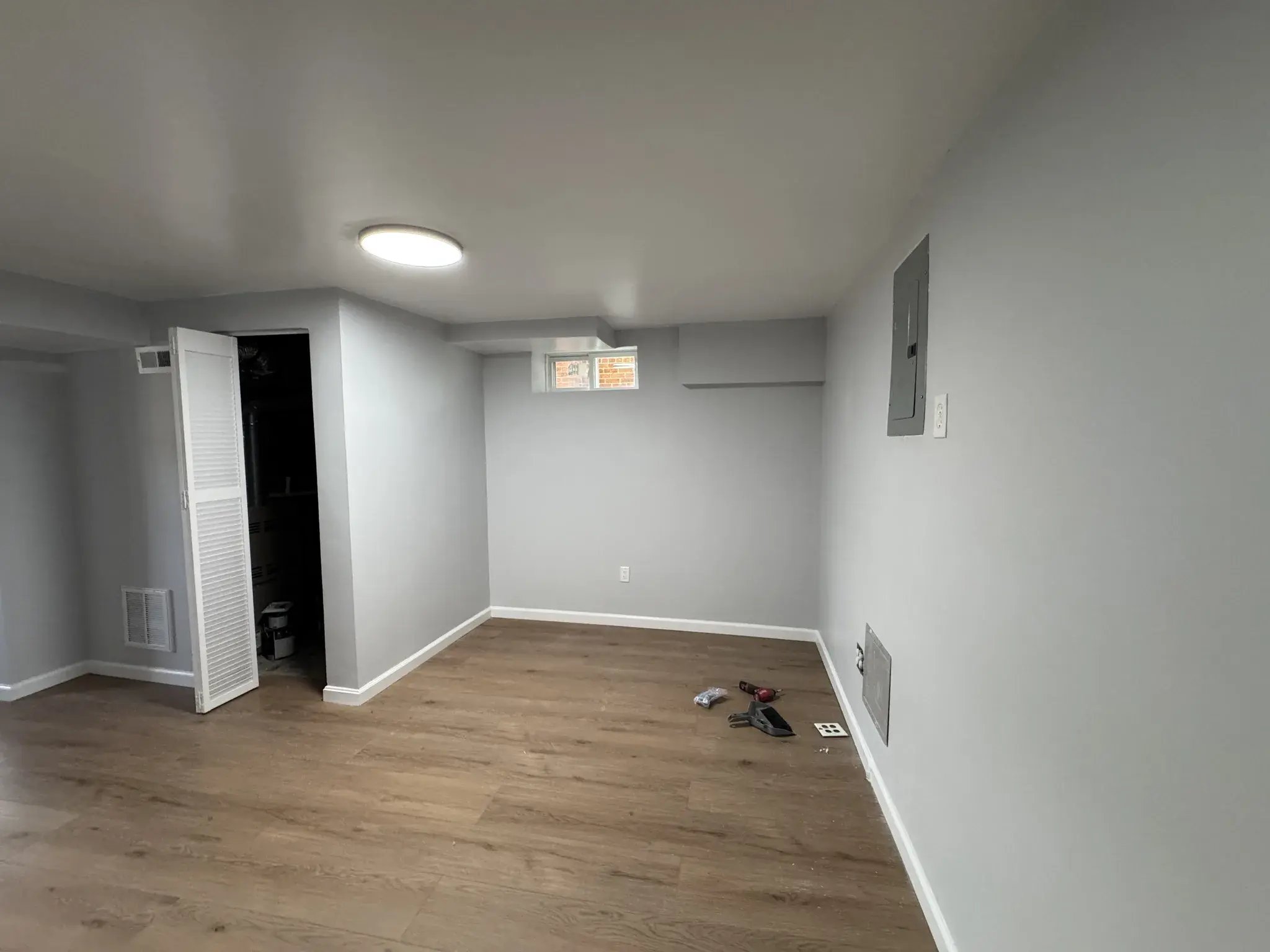 Finished basement room with new flooring and ceiling light