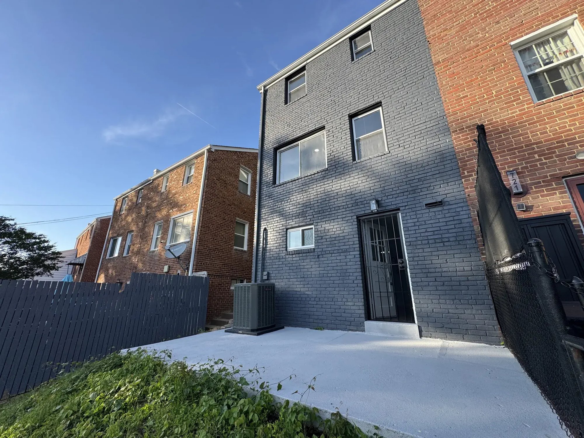 Rear of the house with painted dark gray brick and a clean patio