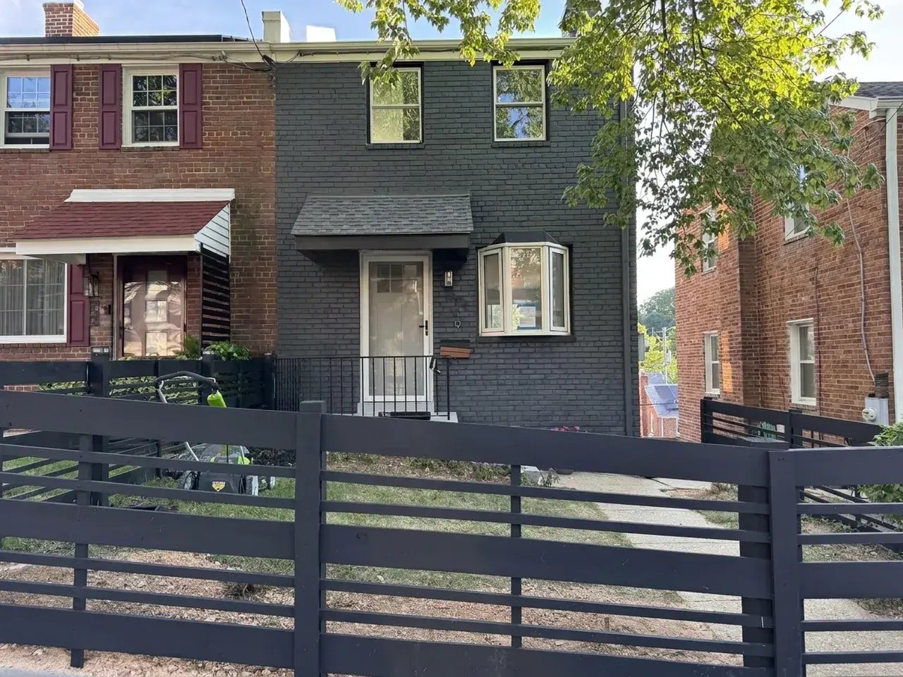 Front of the house with painted dark gray brick and a new horizontal fence