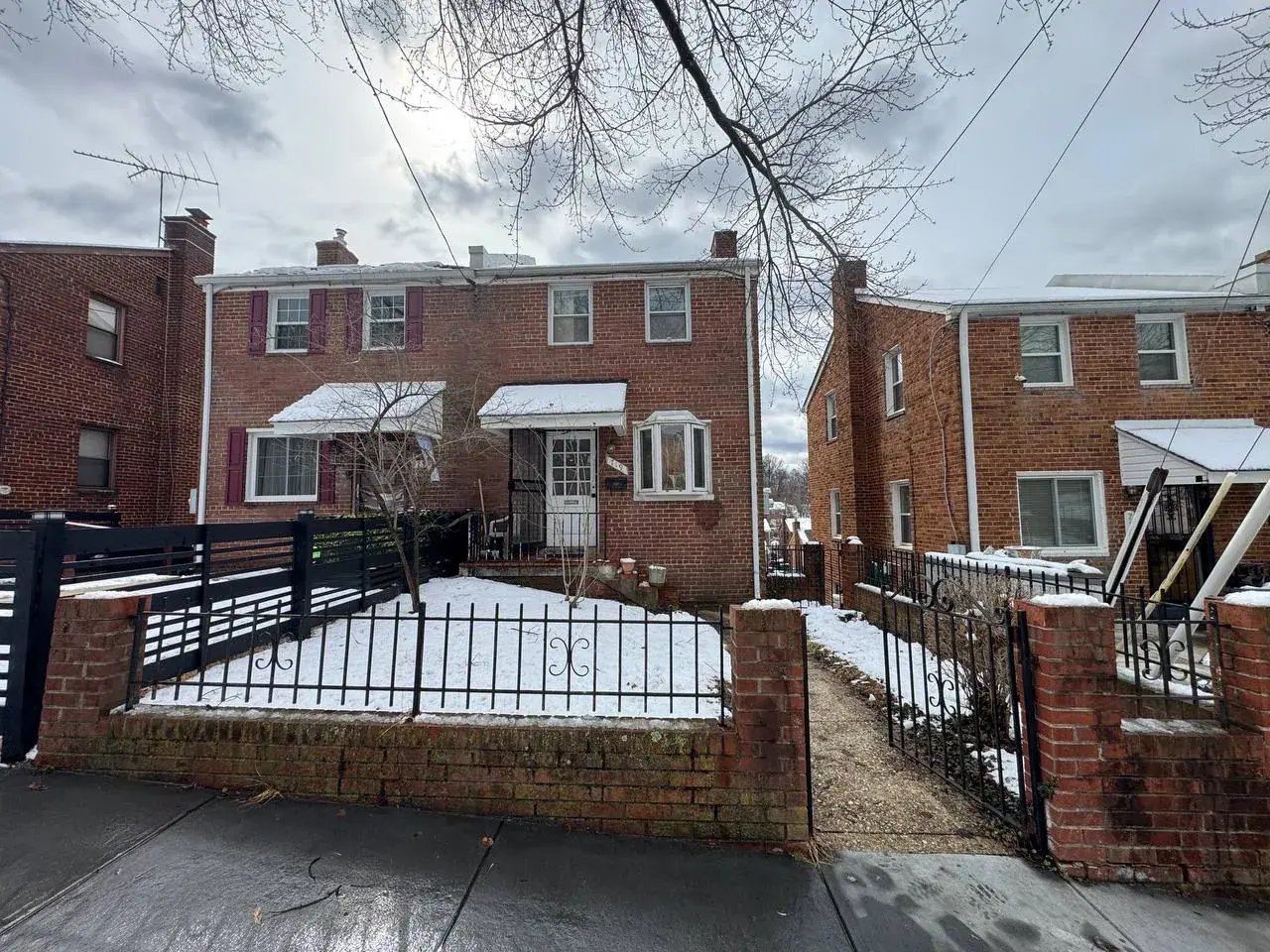 Brick semi-detached house in Washington, DC before renovation, with an old brick and iron front wall