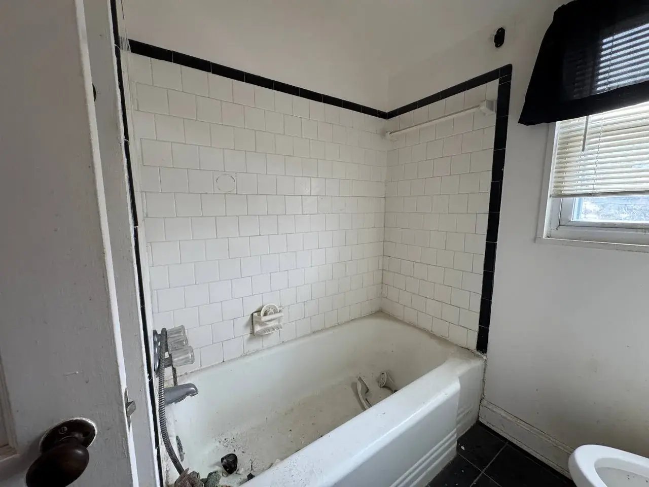 Old bathroom with a worn tub and tile before renovation