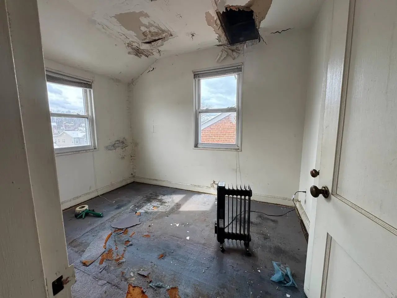 Bedroom with a damaged ceiling and floor before renovation