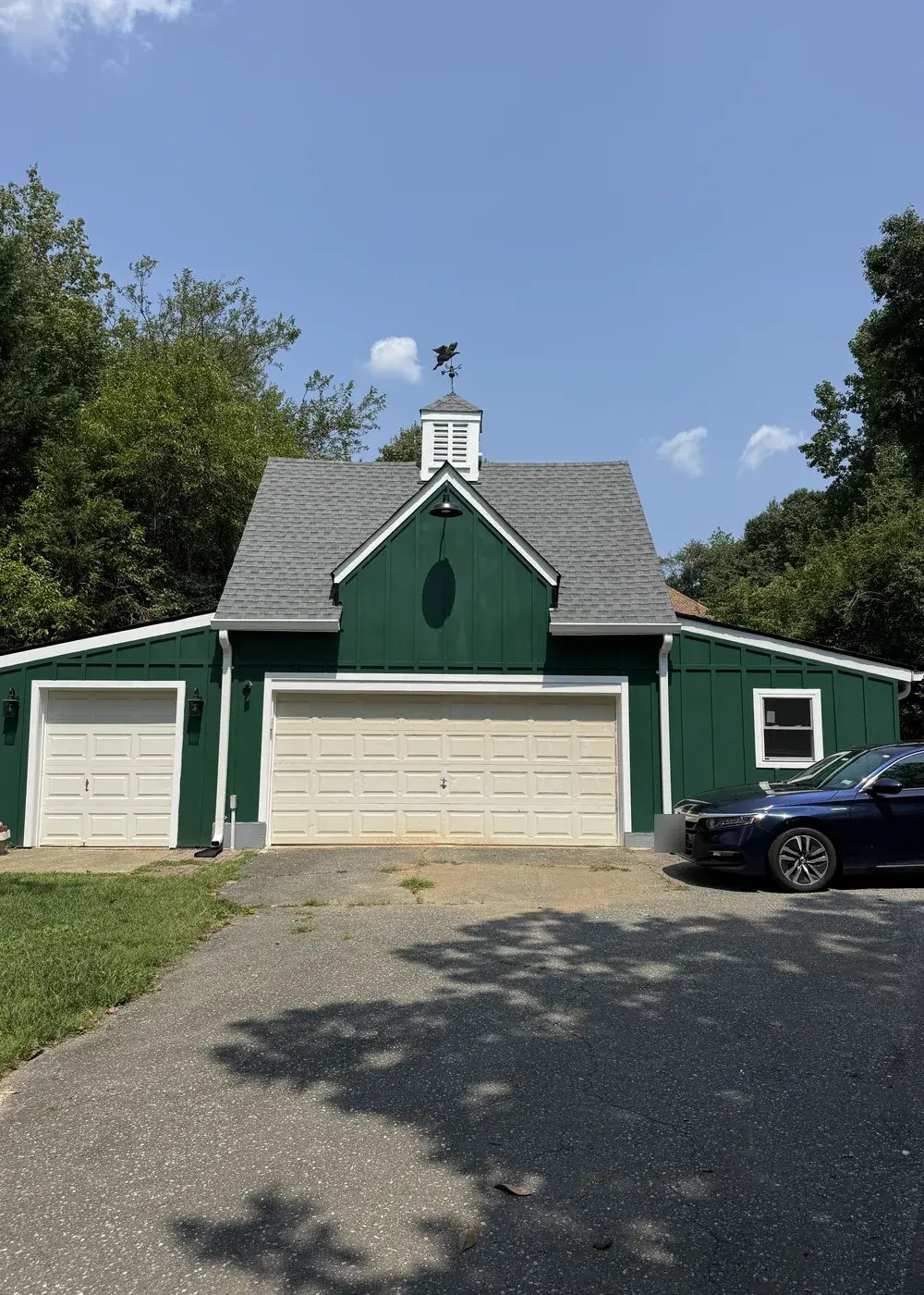 Front of the renovated garage with green siding and new garage doors