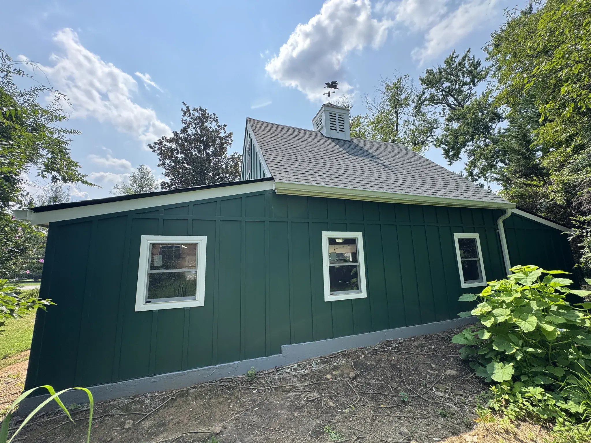 Rear wall of the renovated garage with new windows and green siding
