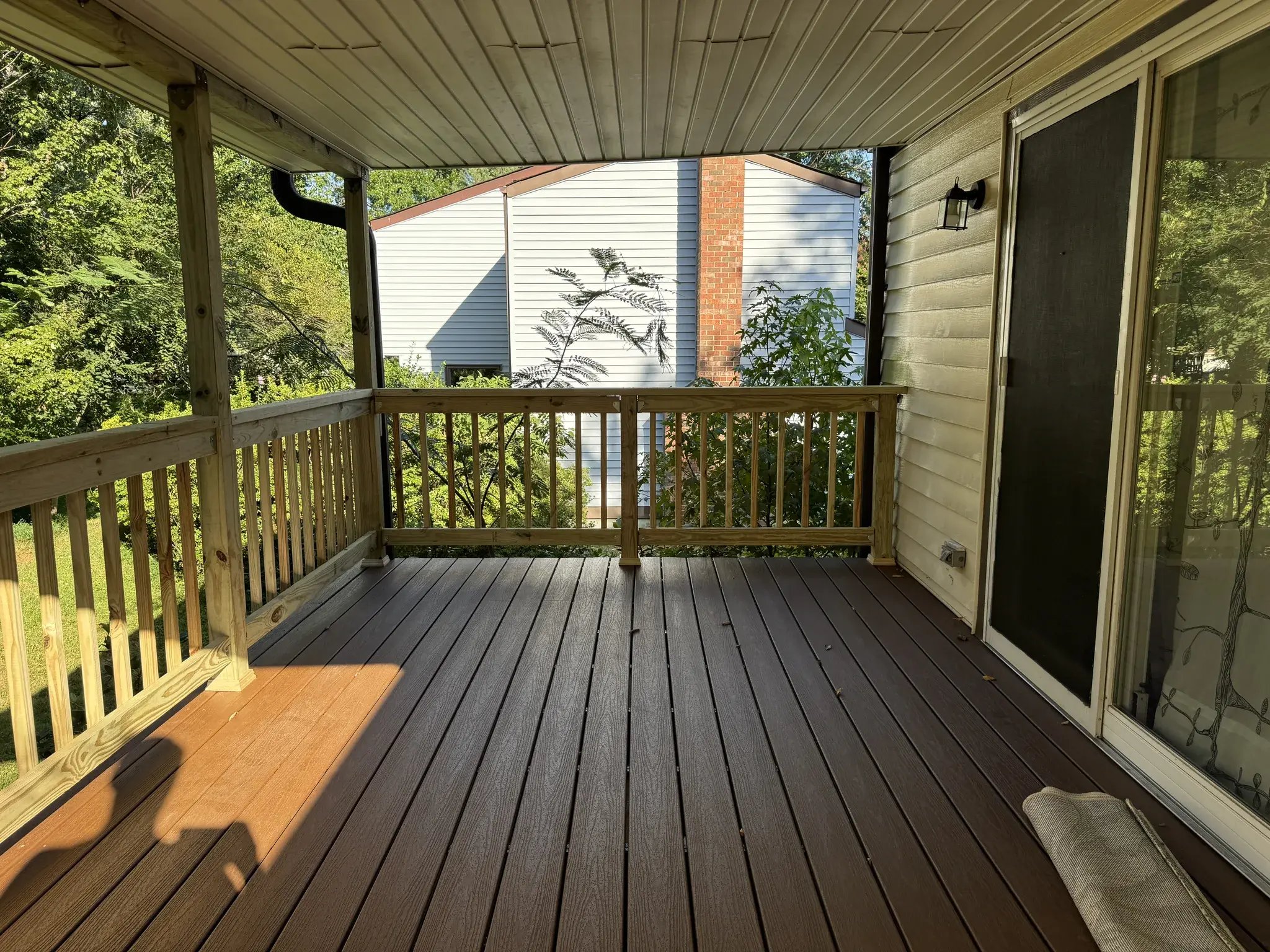 New covered deck next to the sliding door, composite decking in the sun