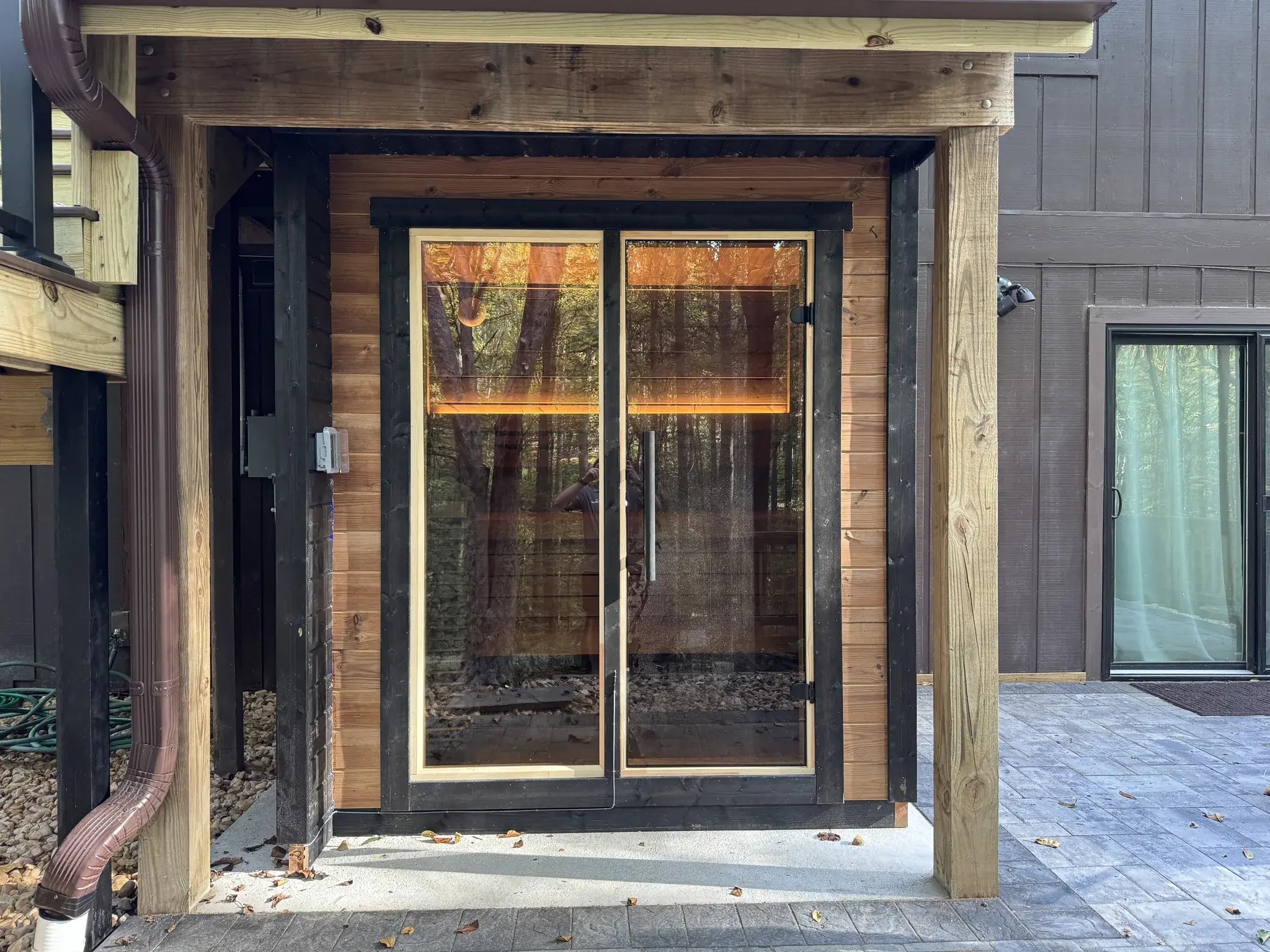 Outdoor sauna with glass doors under the upper deck
