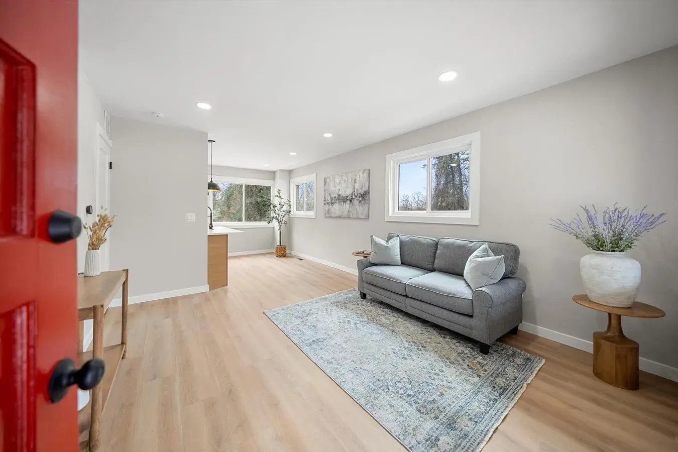 Renovated living room with recessed lights and new light wood plank flooring