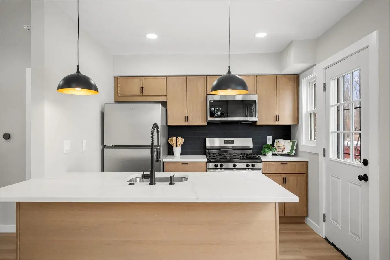 Kitchen with island, pendant lights and light wood cabinets after a whole house renovation