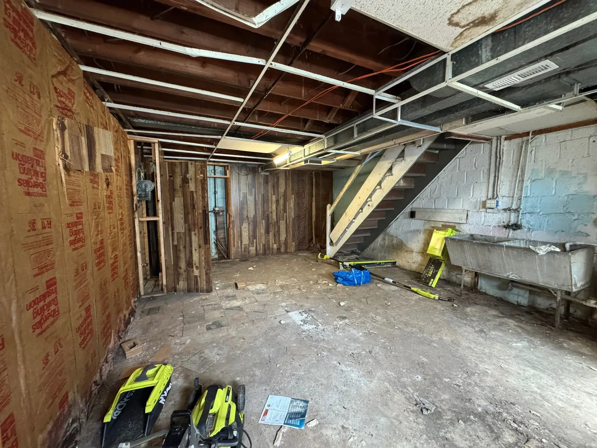 Basement during demolition with insulation exposed and old stairs